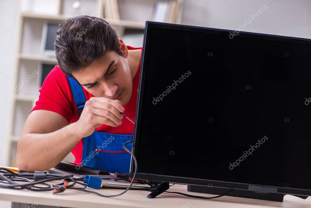 Tecnico che controlla un monitor acceso sul banco di lavoro
